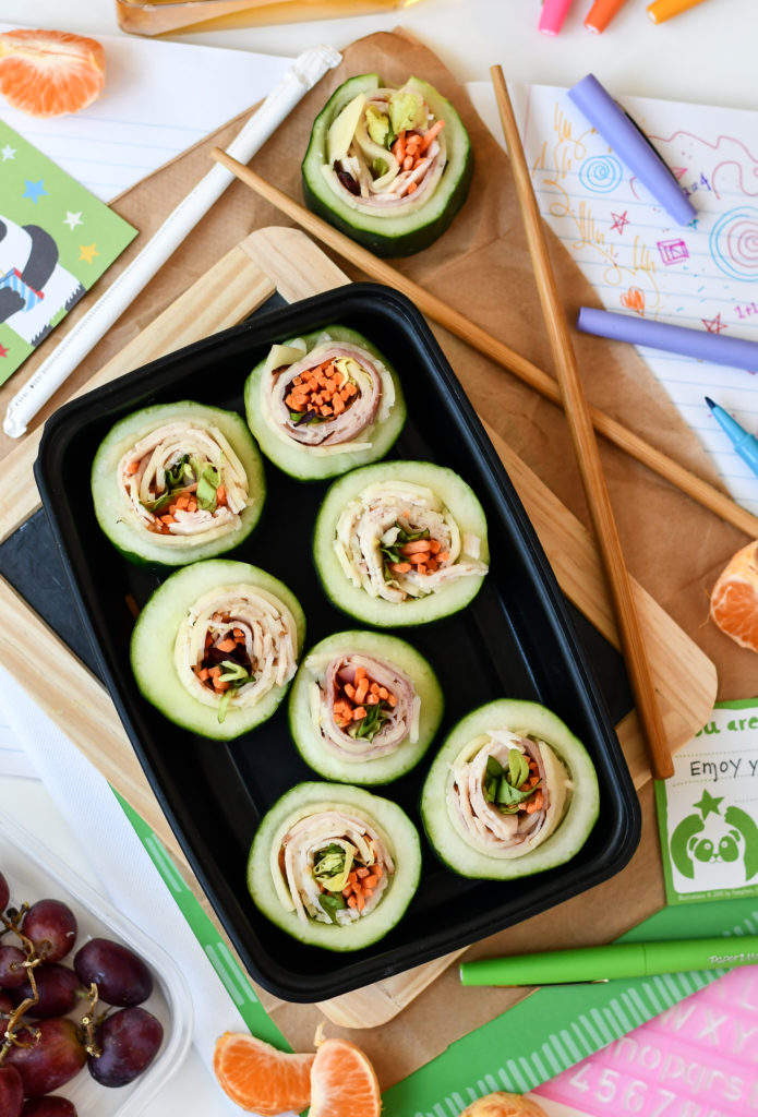 A black container with 7 Cucumber Sushi rolls on top of a lunchbox theme.