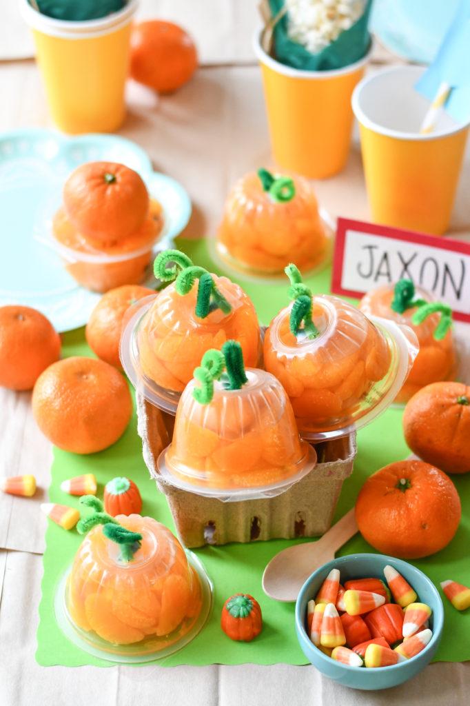  mandarin orange cups made to look like pumpkins with a green background