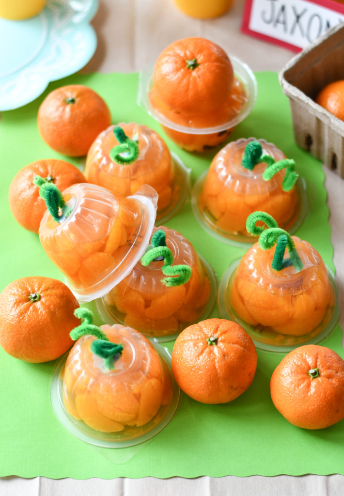 mandarin orange cups made to look like pumpkins with a green background